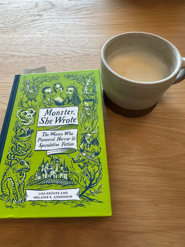 Cover of Monster, She Wrote with a tea latte in a cozy mug. 