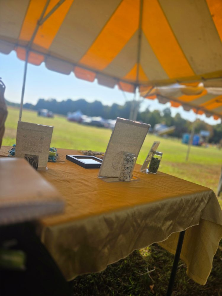 Photo of the backside of one of my tables, using jars of crystals as weights to hold down some of my signage.