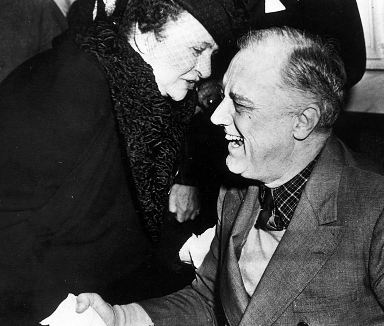 Frances Perkins shaking hands and laughing with President Roosevelt