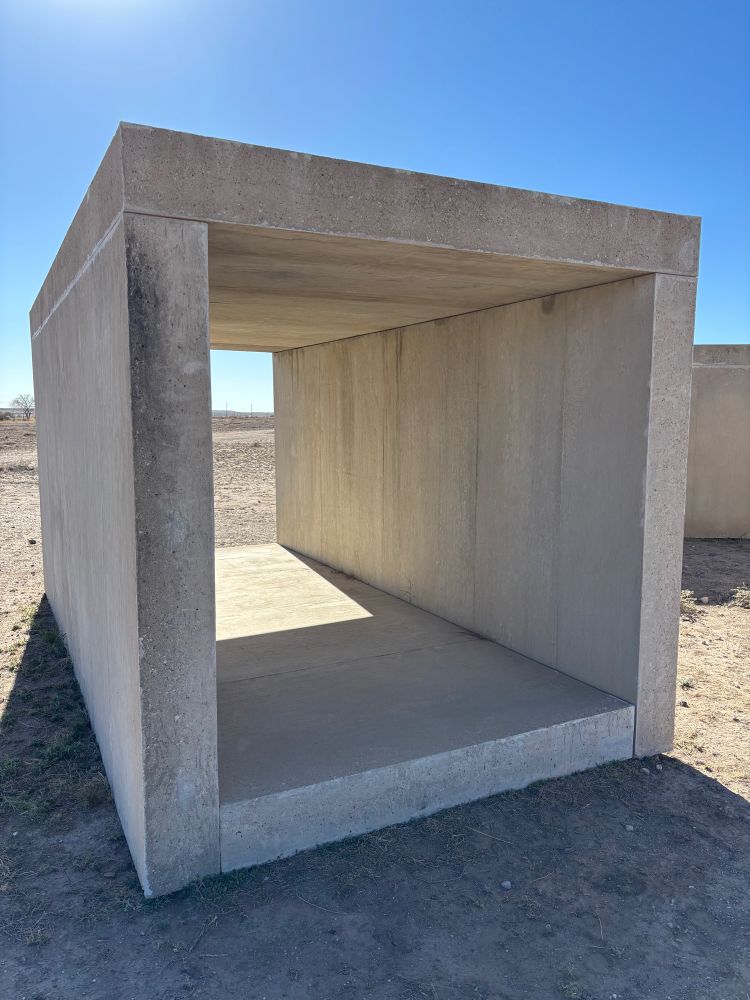 Slightly different angle of Donald Judd concrete box high contrast shadow against bright blue sky.