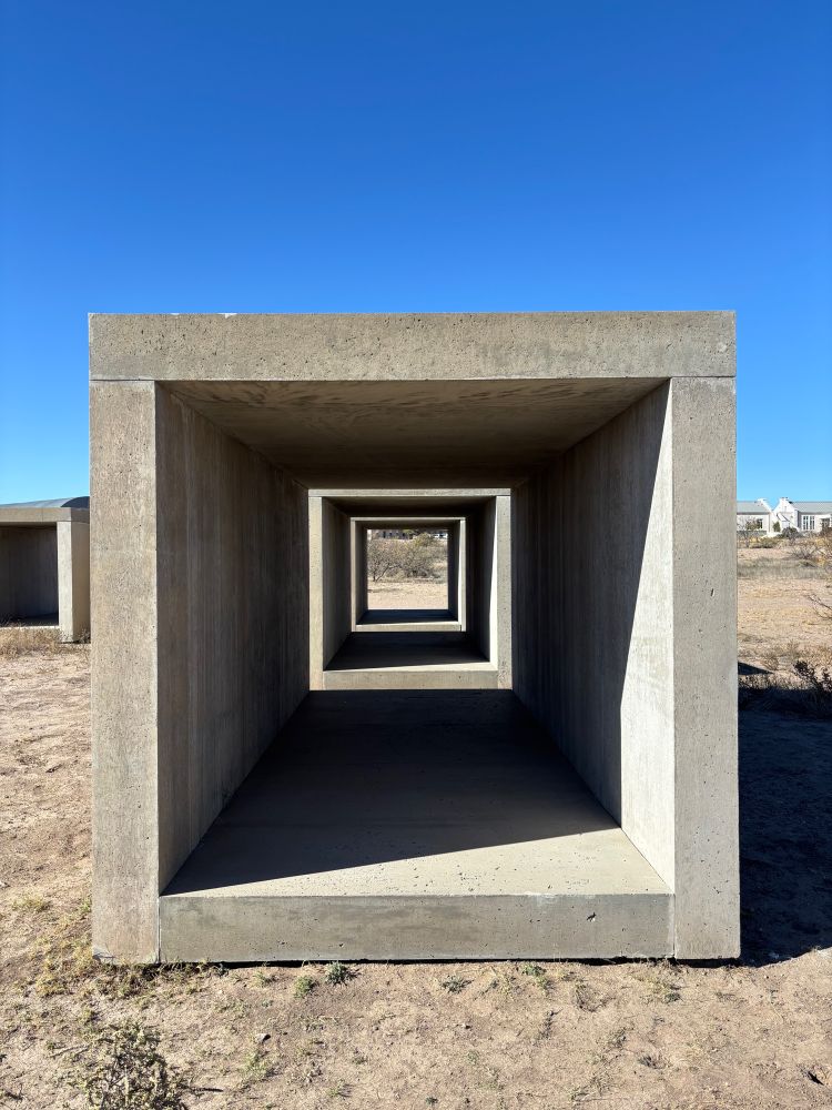 Donald Judd concrete box high contrast shadow against bright blue sky.