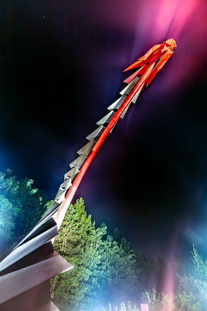 Metallische Drachenskulptur. Bei Nacht. Von direkt unterhalb fotografiert.