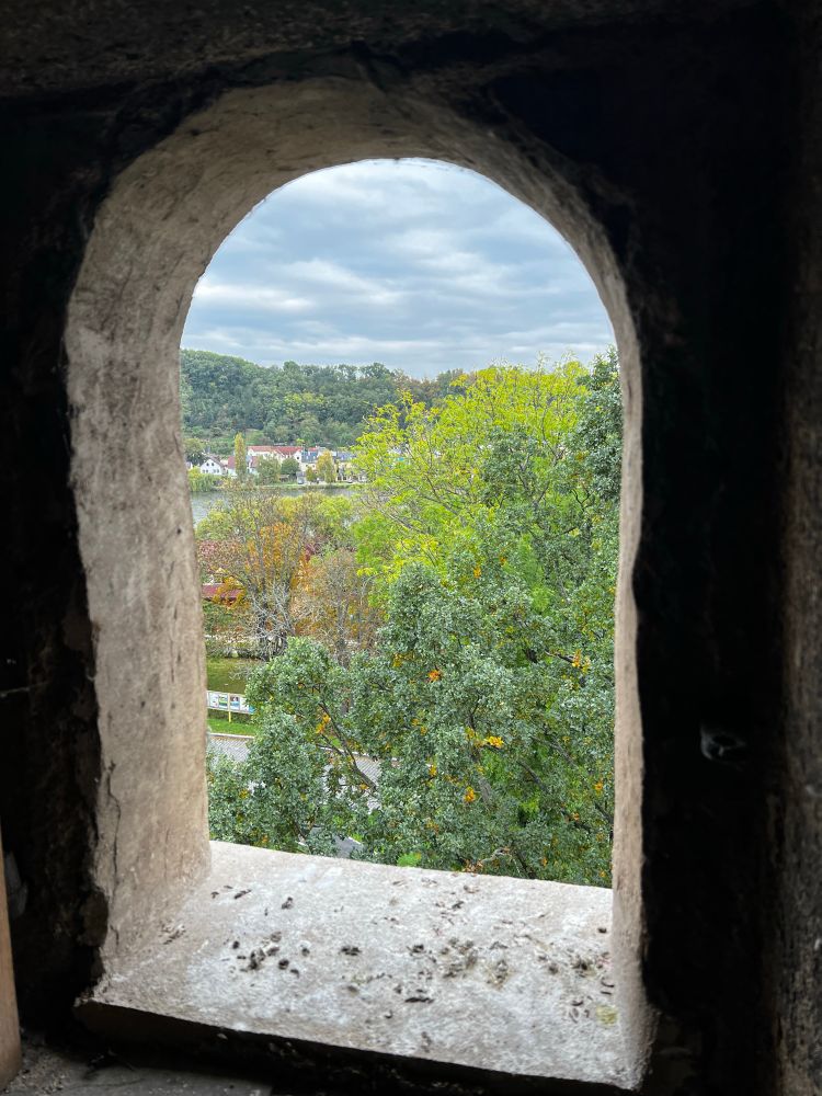 Výhled z okna s půlkruhovým obloukem na kostelní věži směrem k rybníku. 