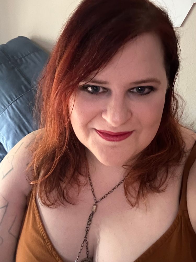 Kat, a woman with red hair wearing an orange dress 