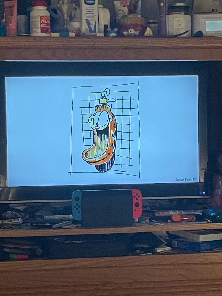 A television displays a white background with a color sketch of a Garfield-themed urinal. The urinal has eyes that would be eye level an average adult, and he is smiling, his mouth wide open to accept whatever is emptied into it