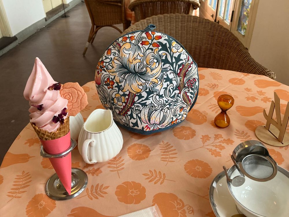 Pink ice-cream with dried rose petals, floral tea cosy, cup with strainer basket to catch tea-leaves, and a small sand-timer