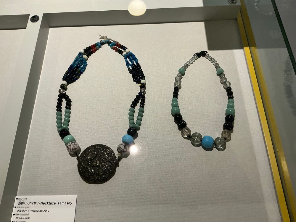 Two large necklaces, one of which has a medallion at the end.