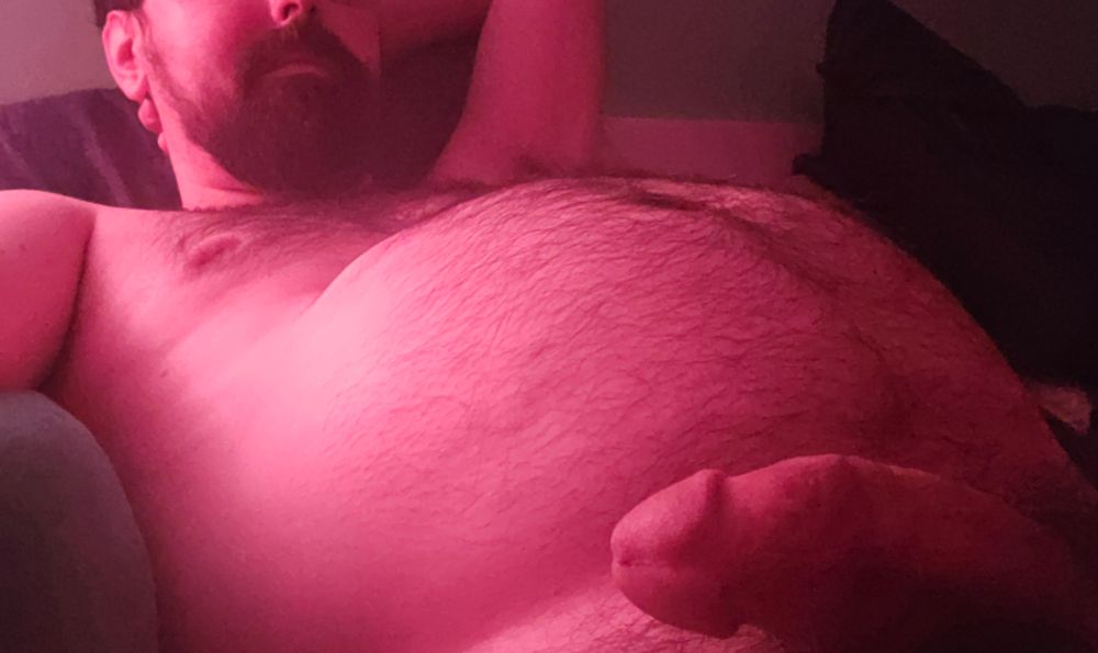 A pup in recline, glowing pink in the lamp light. Tummy ready for rubs and bone ready for whatever happens next