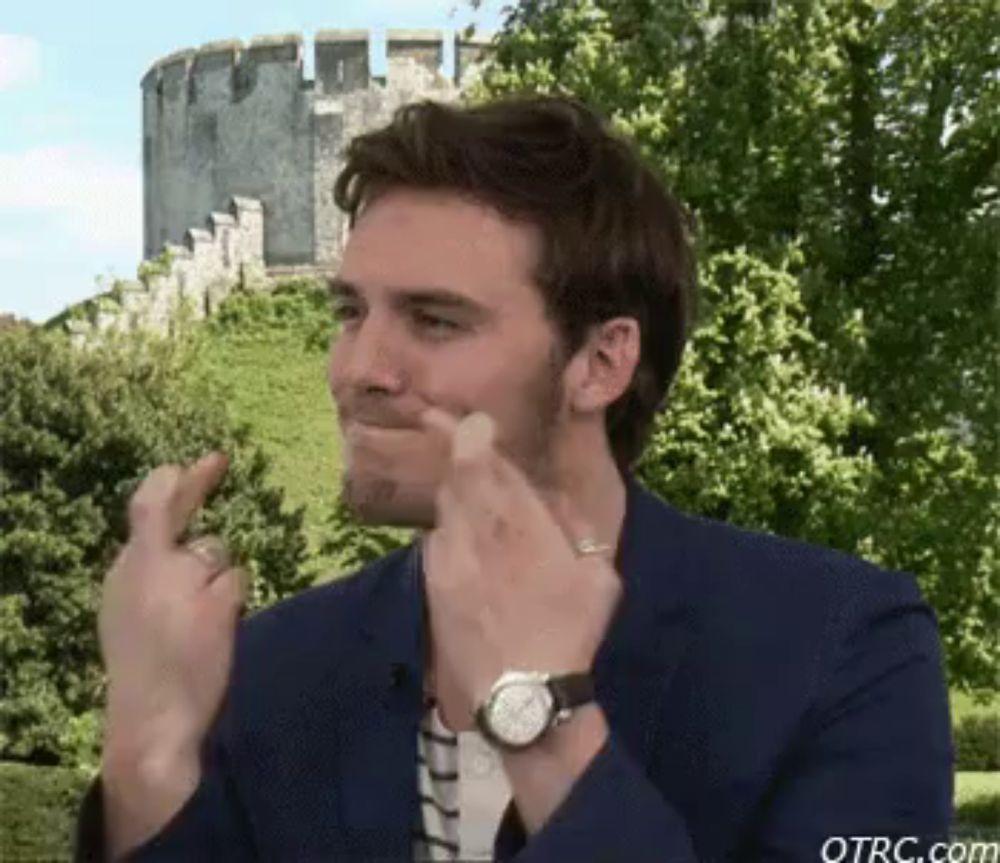 a man wearing a watch is making a face in front of a castle .