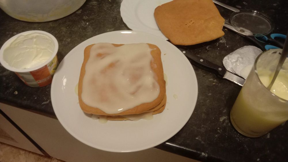 a stack of three cake layers with cream seen in the gaps and covered with cream atop. the cream is white and is definitely cream and not what you're probably thinking about
