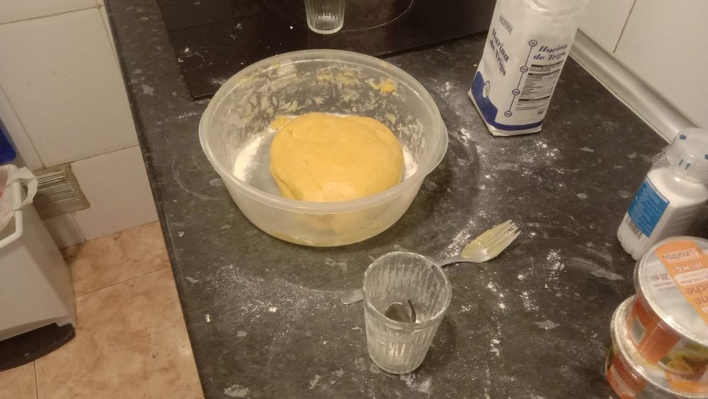 a lump of dough in a container amidst lots of spilled flour. kinda photobombed by a fork i used to mix it with in earlier stages