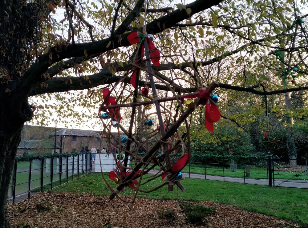 An outdoor Christmas decoration made from baubles, ribbons and twigs.