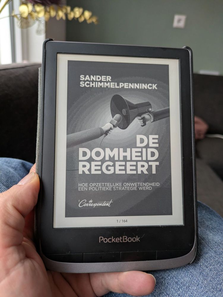 Foto van e-reader met de cover van het boek De Domheid Regeert van Sander Schimmelpenninck, uitgegeven door de Correspondent