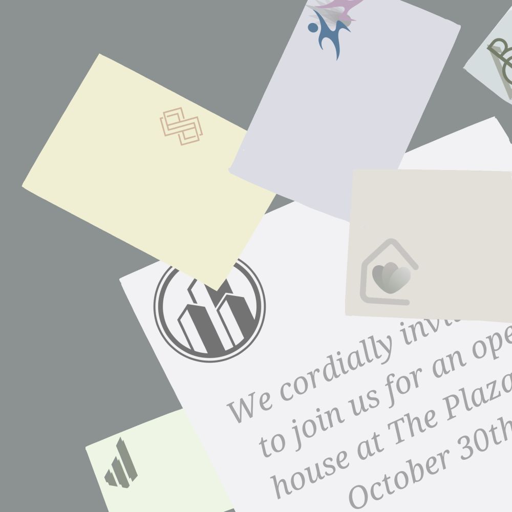 Several business cards, blank except for logos, strewn across a desk. One flyer beneath them, partially obscured, reads: "We cordially invite you to join us for an open house at The Plaza on October 30th".