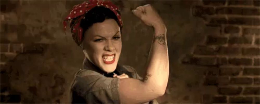 a woman is flexing her muscles in front of a brick wall while wearing a red headband .