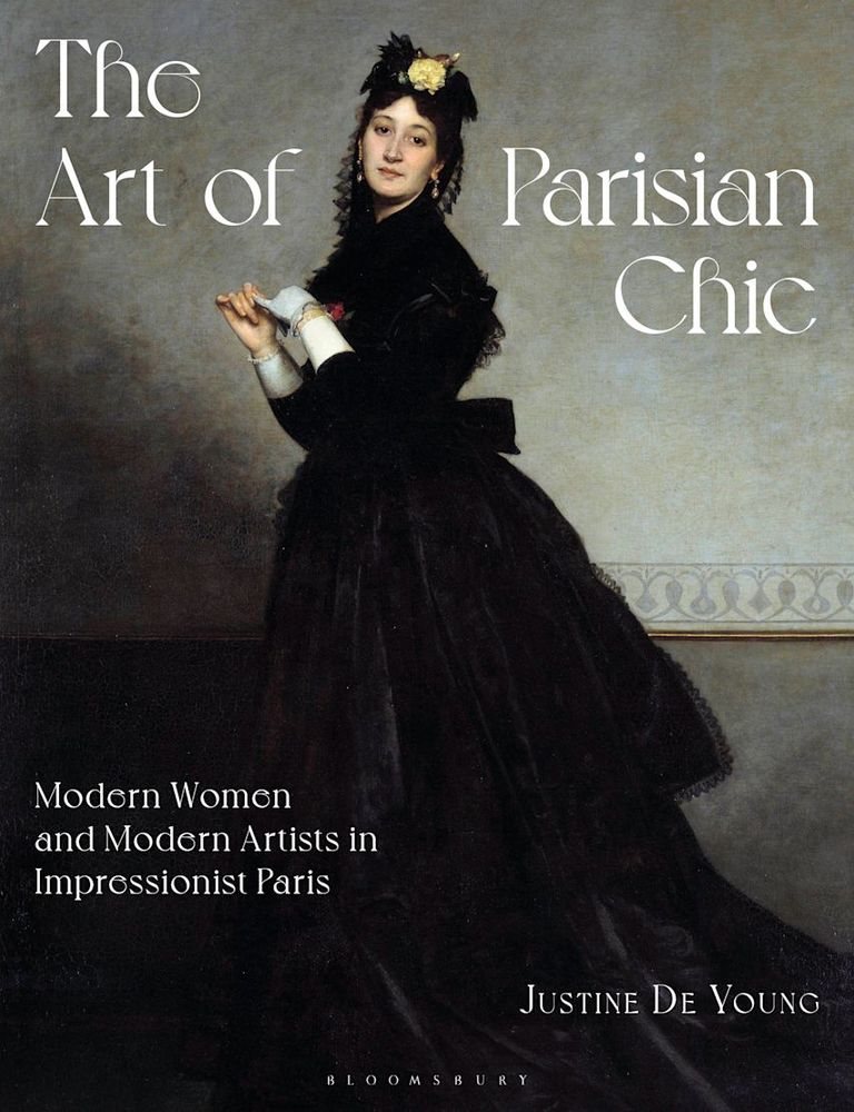 The Art of Parisian Chic: Modern Women and Modern Artists in Impressionist Paris by Justine De Young. (Bloomsbury 2025). White woman in black dress standings against a gray wall, staring out at the viewer while she pulls off one of her gray gloves. Yellow rose on her hat, red bud at her breast.