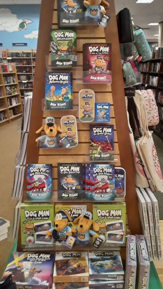 A shelf display of Dog Man books- There are also board games, card games, and puzzles- 