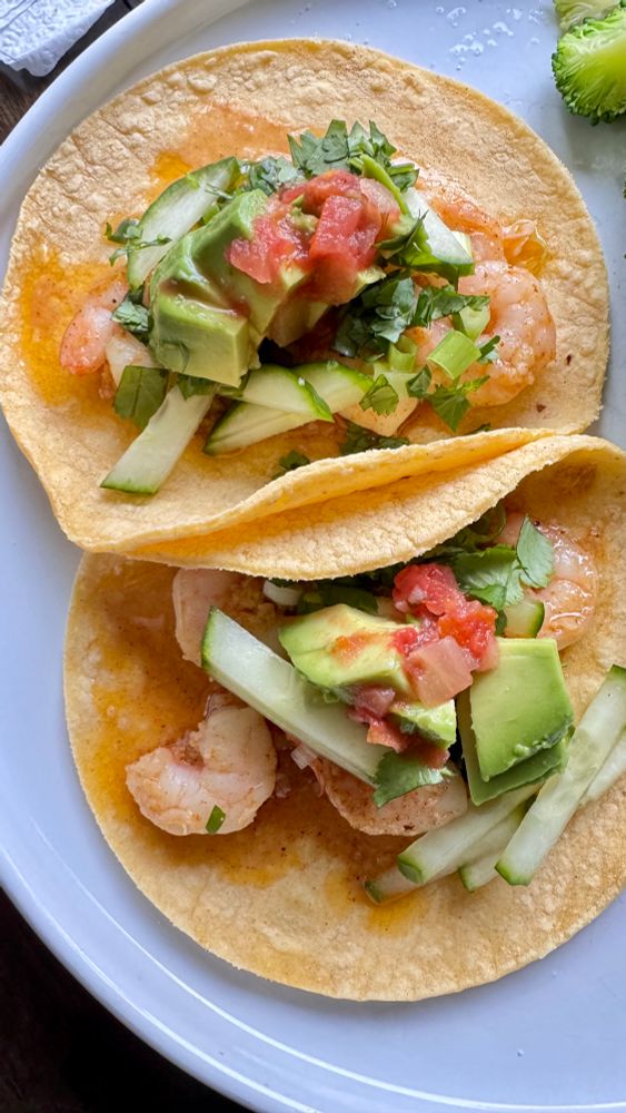 Shrimp tacos with green onion, cucumber, avocado, cilantro and salsa