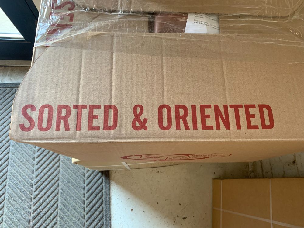 A cardboard box with "sorted and oriented" stamped on the outside.
