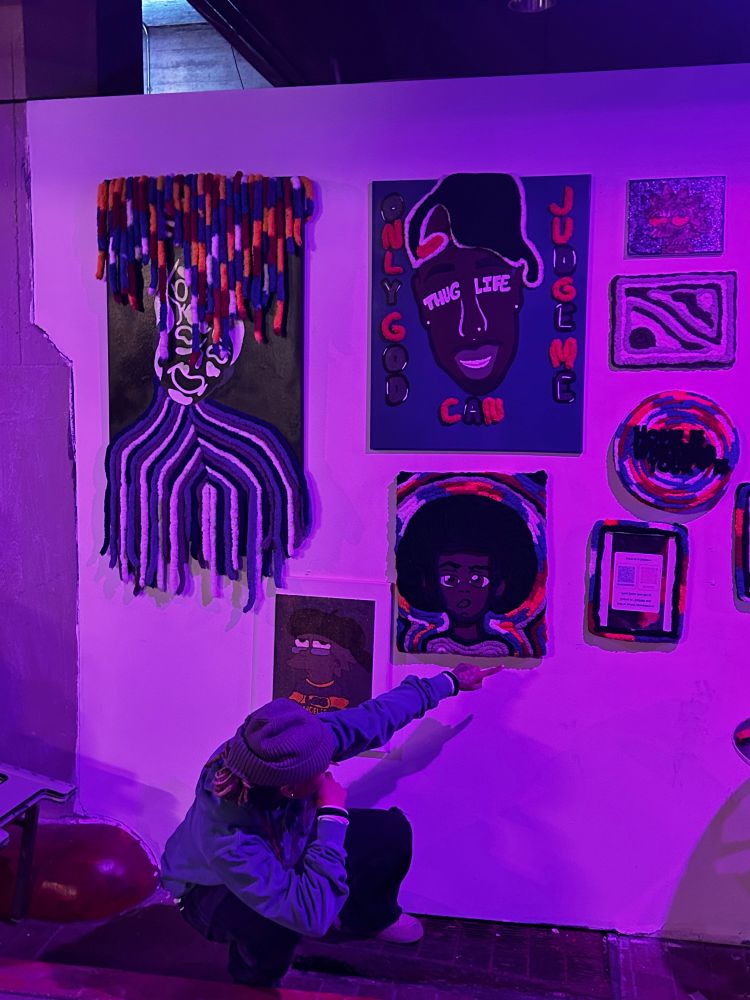 Same as the other photo except now I’m turned around pointing at a decorative plaque of the artist’s social media accounts (Soul Woven Creations) 