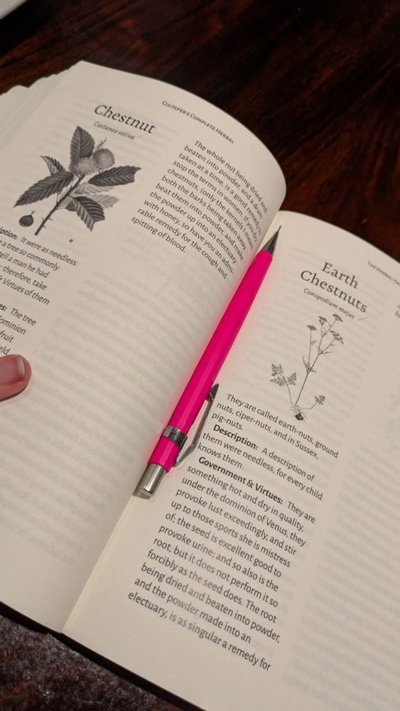 An open spread of Culpeper's Herbal with a neon pink mechanical pencil sitting on it. 