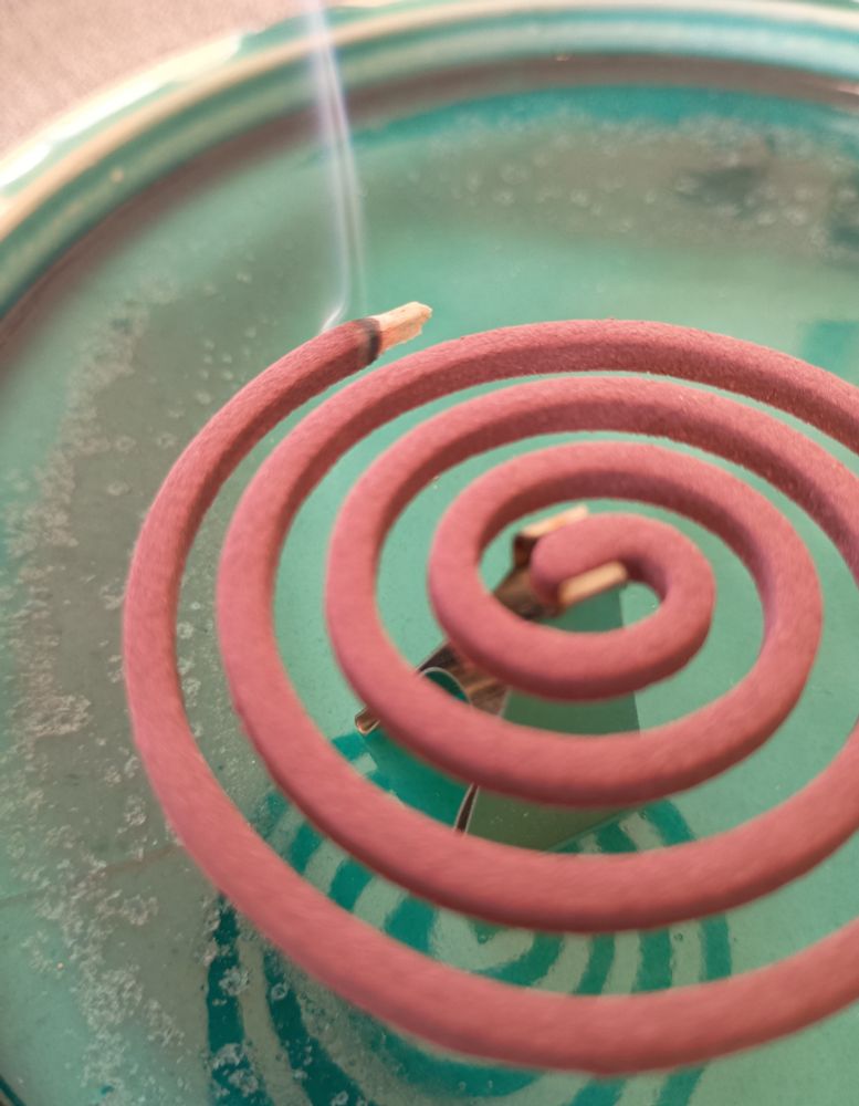 ターコイズブルーのお皿の上に、渦巻の紫色のお香　白煙の筋が上がっている　松栄堂　白川