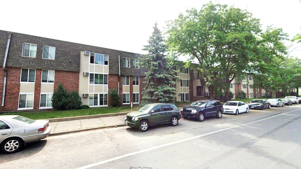 photo of 3 story apartments in alternating brick and yellow wood, the wood part is where sliding glass doors and balconies were once located. 