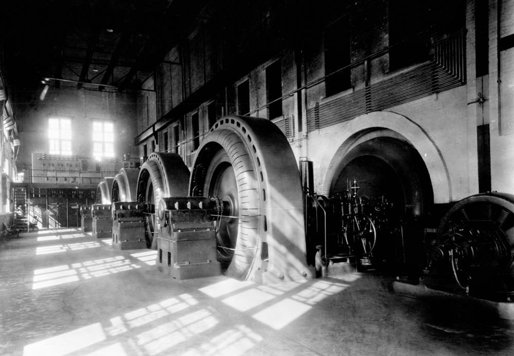 black and white photo of 4 of the large turbines inside the powerhouse at the lower St Anthony Falls hydro station, 1890s. 
