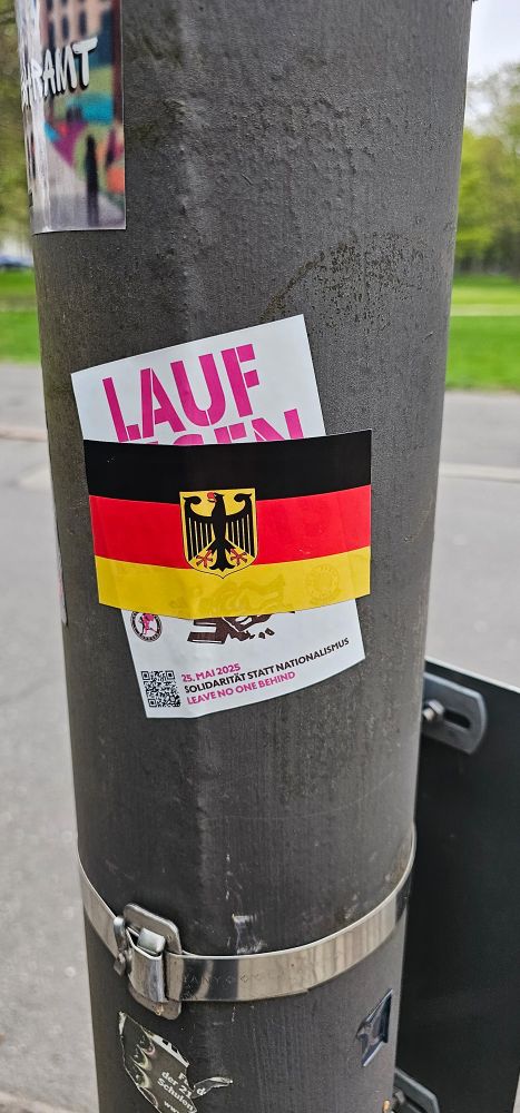 Aufkleber mit Deutschlandflagge überklebt einen Aufkleber, der den Lauf gegen Rechts bewirbt.
