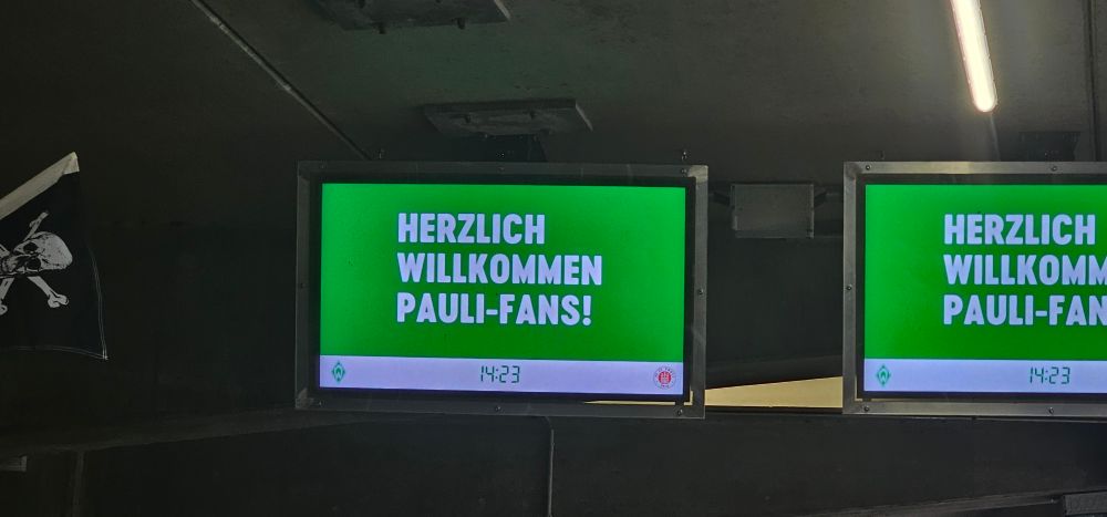 Monitor am Weserstadion. Weiße Schrift auf grünem Grund "Herzlich willkommen Pauli-Fans!"