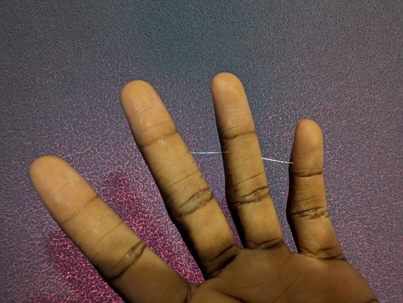 a close up of my fingers spread out. there's two strings of pre-cum linking my middle finger, ring finger, and pinkie. the colors are unedited so the strings are really shiny and visible