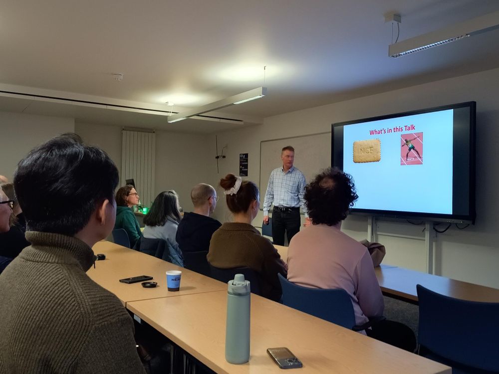 man stood in lecture theatre in front of an audience.