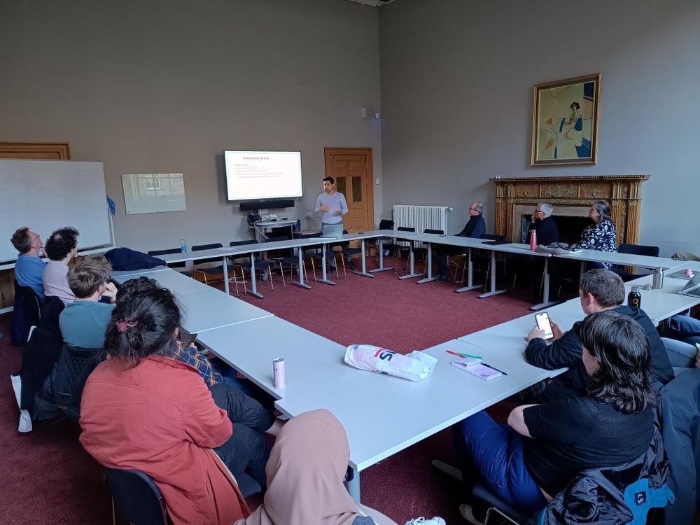 square room with man presenting at a TV screen.