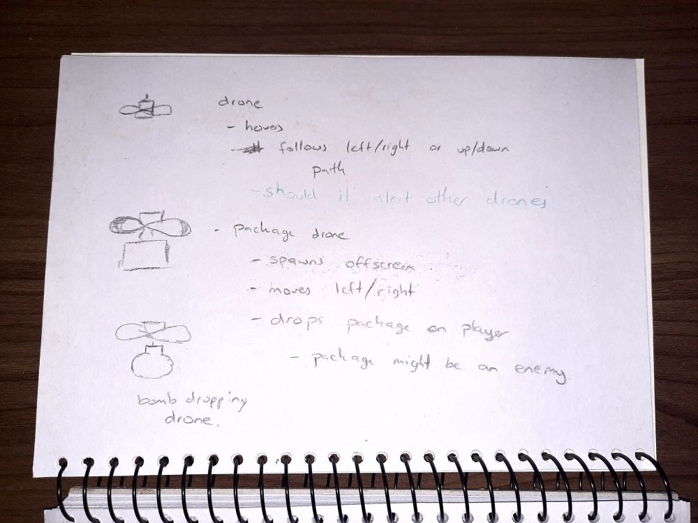 Photo of a spiral sketchbook showing 3 drone ideas.

- Drone: hovers, follows left/right or up/down path.
- Package drone: spawns offscreen, moves left/right, drops package on player, package might be an enemy.
- Bomb dropping drone.