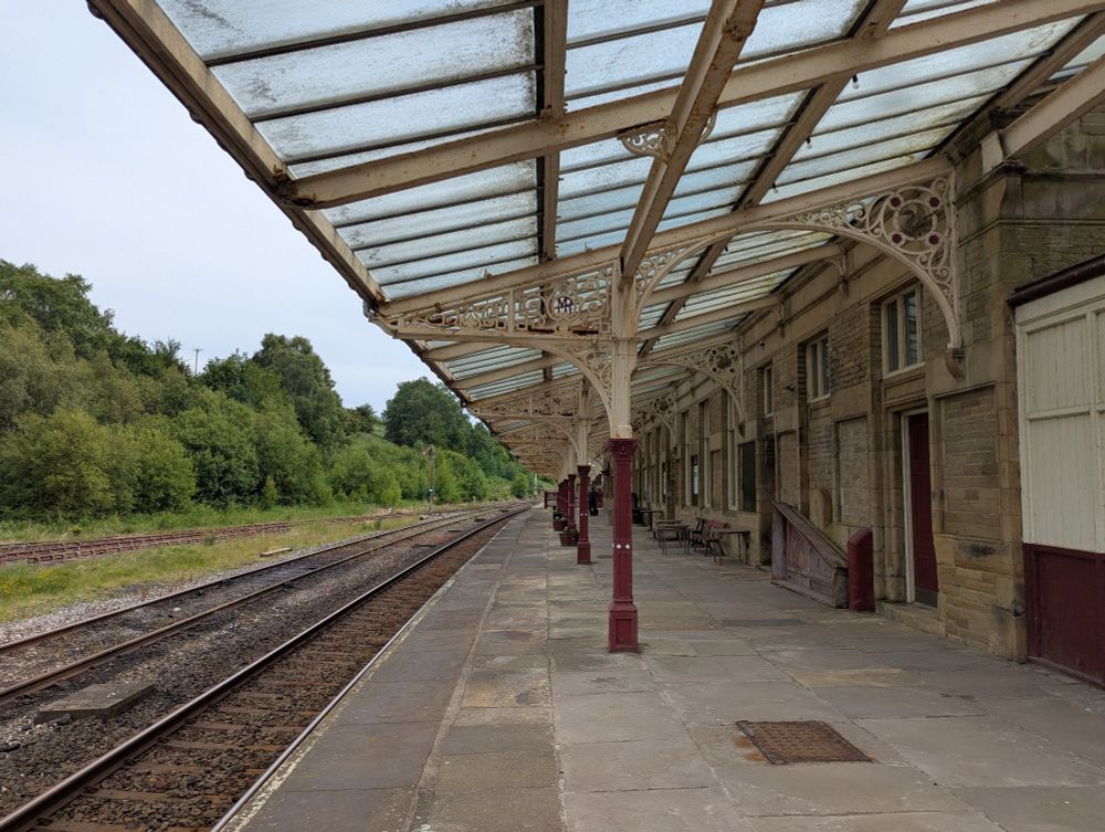 Cream and red canopy with glass roof, stone building to the left, stone platform in the middle and track to the right