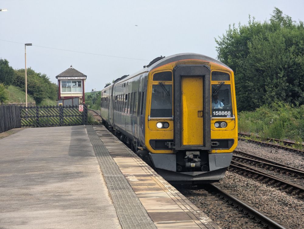 Class 158 arrives into the platform, signal box in the background 