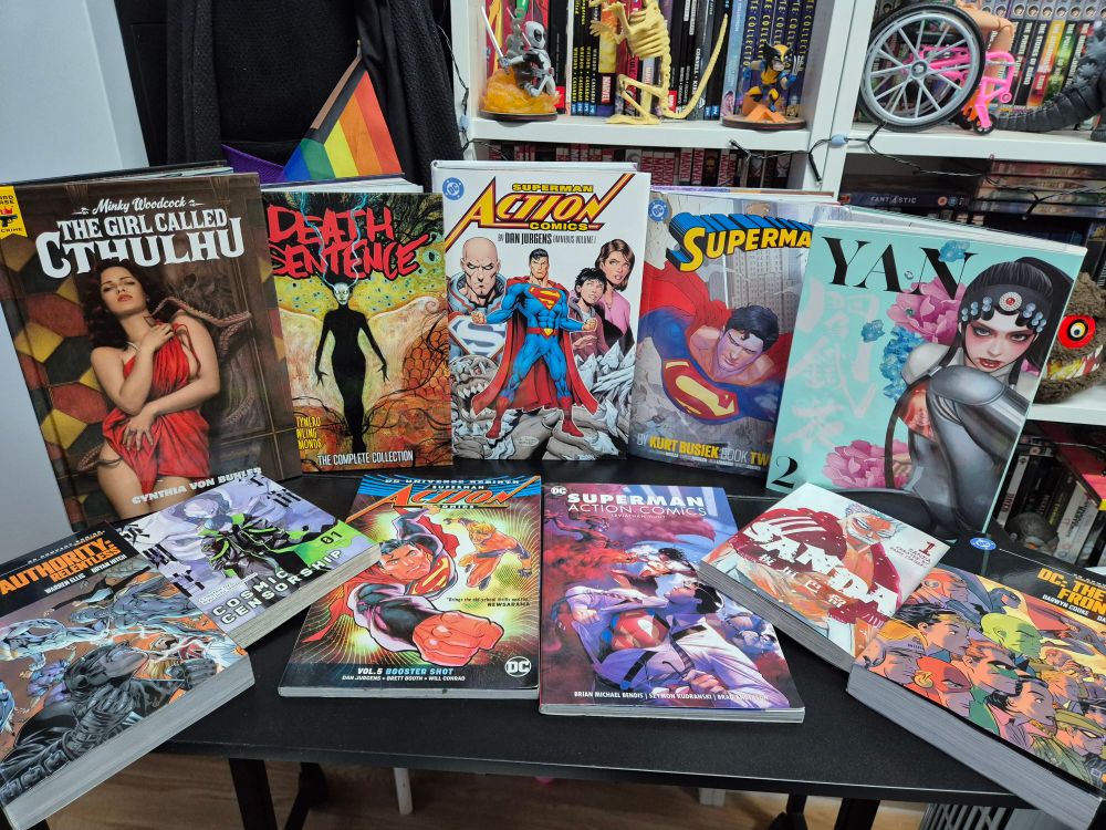 A table covered with graphic novels and manga. They are, Minky Woodcock: The Girl Called Cthulhu, Death Sentence: The Complete Collection, Superman Action Comics by Dan Jurgens: Omnibus Volume 1, Superman by Kurt Budsiek: Book 2, Superman Action Comics: Booster Shot, Superman Action Comics: Leviathan Hunt, Yan Volume 2, DC Compact Classics: The Authority - Relentless, DC Compact Classics: DC The New Frontier, Sands volume 1, Cosmic Censorship volume 1.