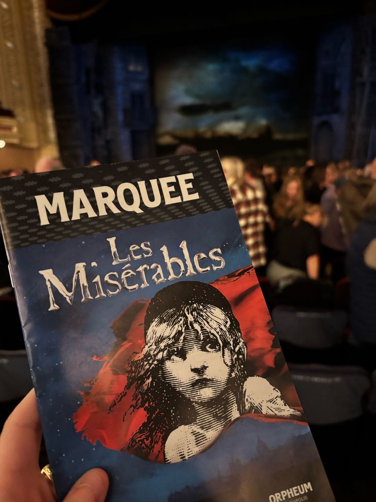 the les miserables marquee program before the performance with the audience and stage in the background 