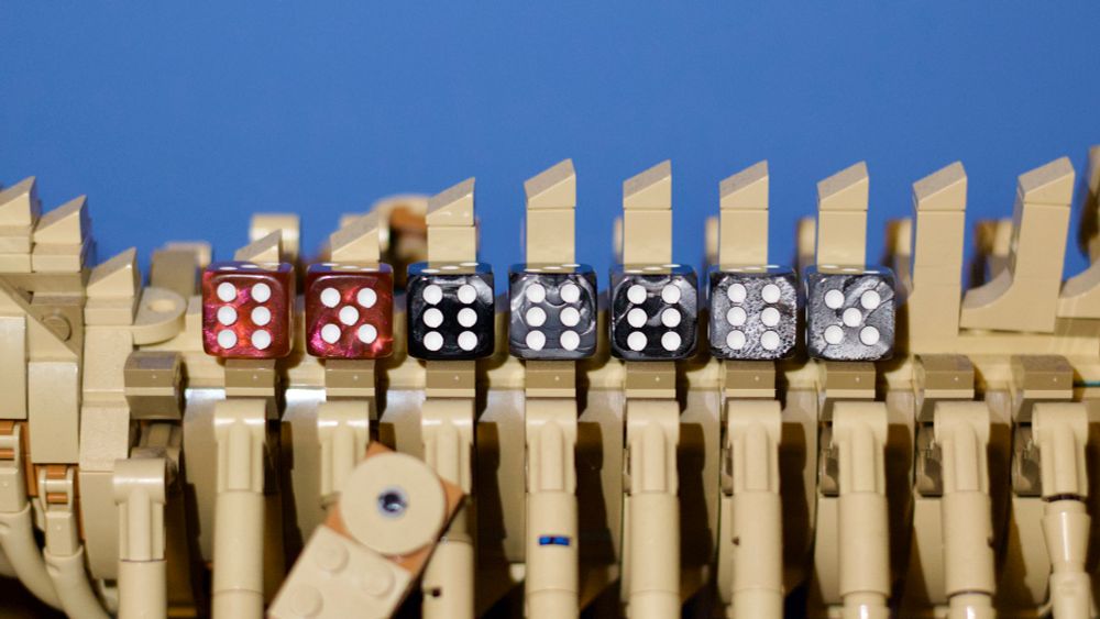 Seven dice along the top of the ribs of the Lego T-Rex set. The left two dice are amber and total 11, the right five dice are grey and total 29.