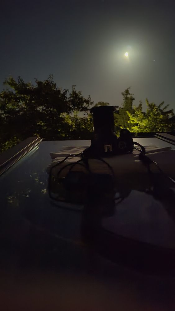 Fotoapparat auf einem waagerechten Dachflächenfenster gen Himmel gerichtet. Strom und Steuergerät daneben. 
