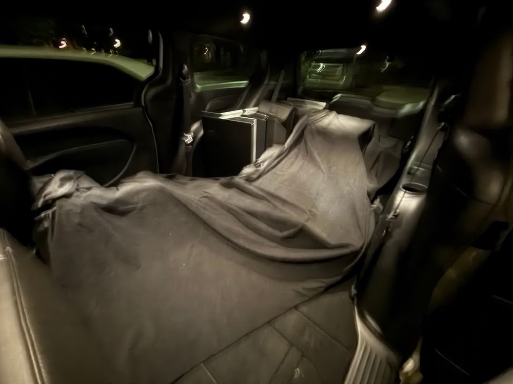 A minivan with a lot of black material covering lumpy shapes