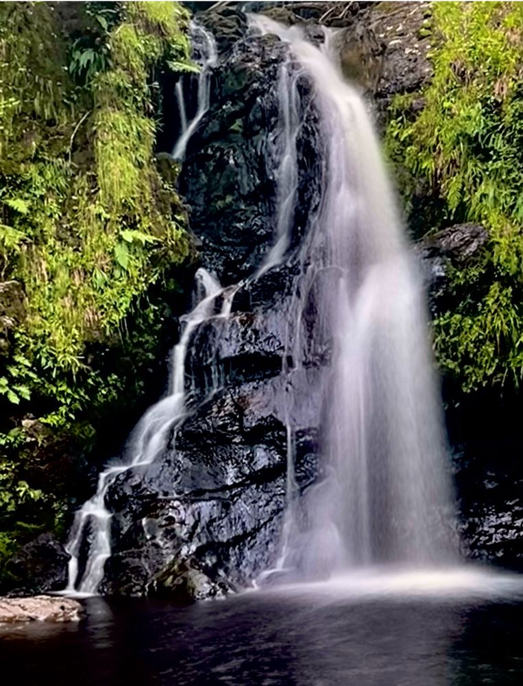 A photograph of a waterfall. The long exposure gives it a wispy look as it cascades down the rocks. 