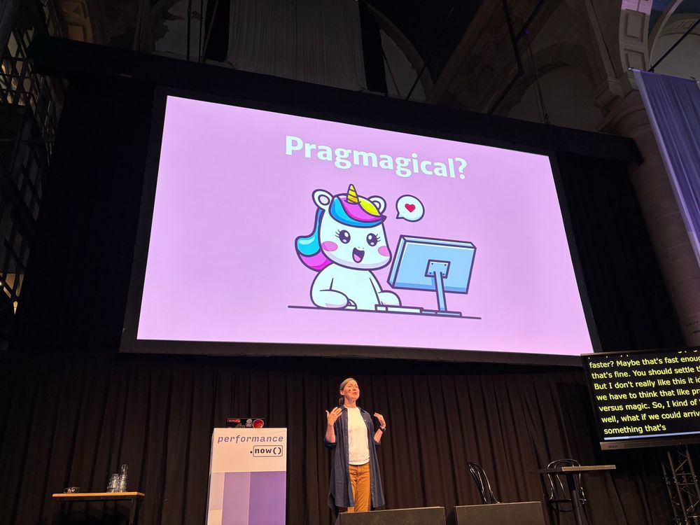 Woman on stage presenting a slide reading Pragmagical with a cartoon unicorn.