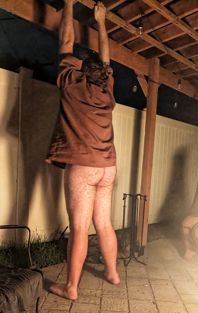 Brock,seen from behind, wearing a shirt and no pants, with his arms stretched above his head