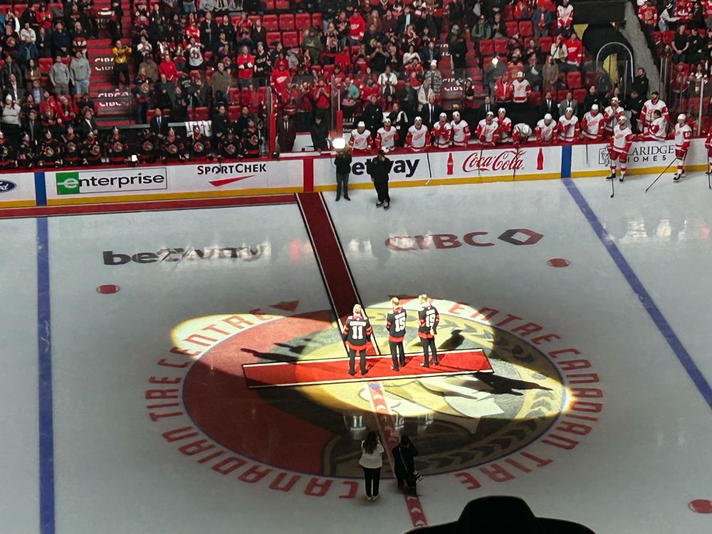 A photo of Jason Spezza #19, Danny Heatley #15, and Daniel Alfredsson #11 at center ice in the Canadian Tire Centre. 