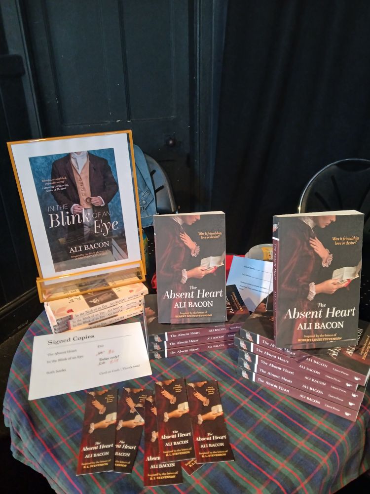 Image shows small table with display of books 'In the Blink of an Eye' and 'The Absent Heart' both by Ali Bacon.