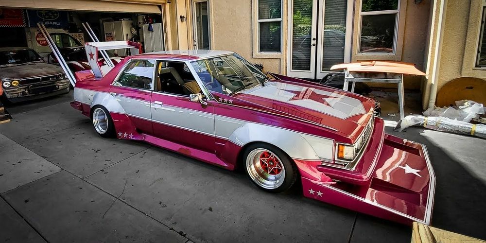 Purplish red bosozoku car with white decals and a huge shelf for a front bumper