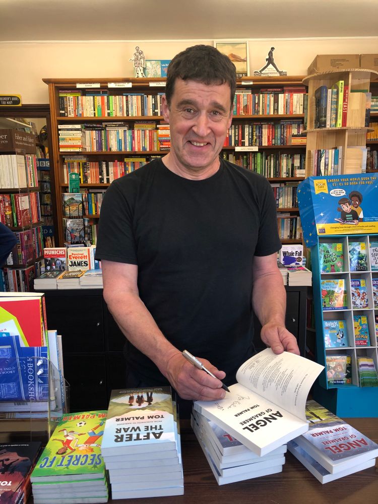 The author Tom Palmer signing copies of his book, Angel of Grasmere inside Sam Read Bookseller, bookshop. 
