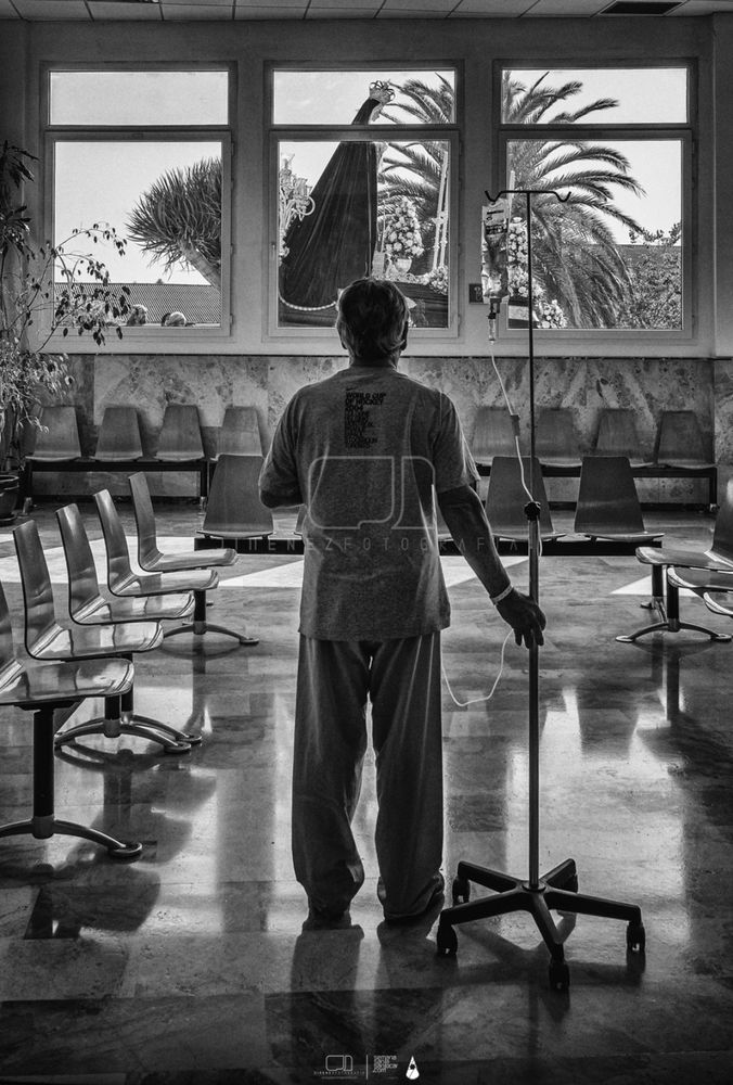 Hombre con un gotero de suero y en pijama, viendo la procesión desde el hospital.  Fotografía de semana santa, José Jiménez