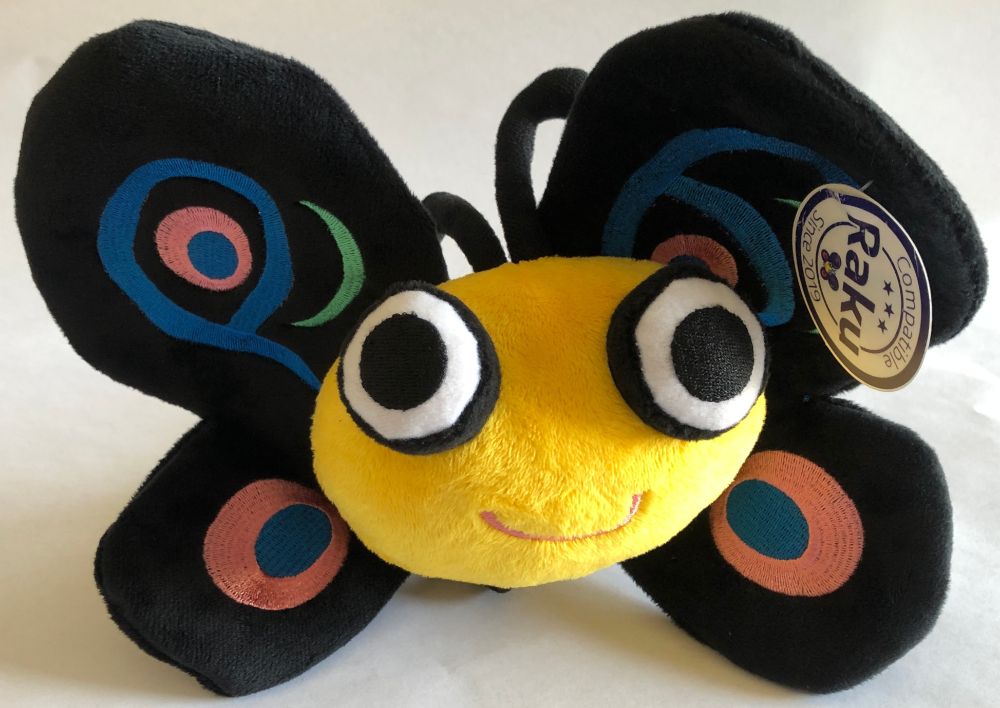 Stuffed toy butterfly Camelia - mascot of the programming language Raku - yellow body with a smile and big beady eyes, black wings adorned with a P and a 6. Two antennae on top of her head, and four black legs underneath.